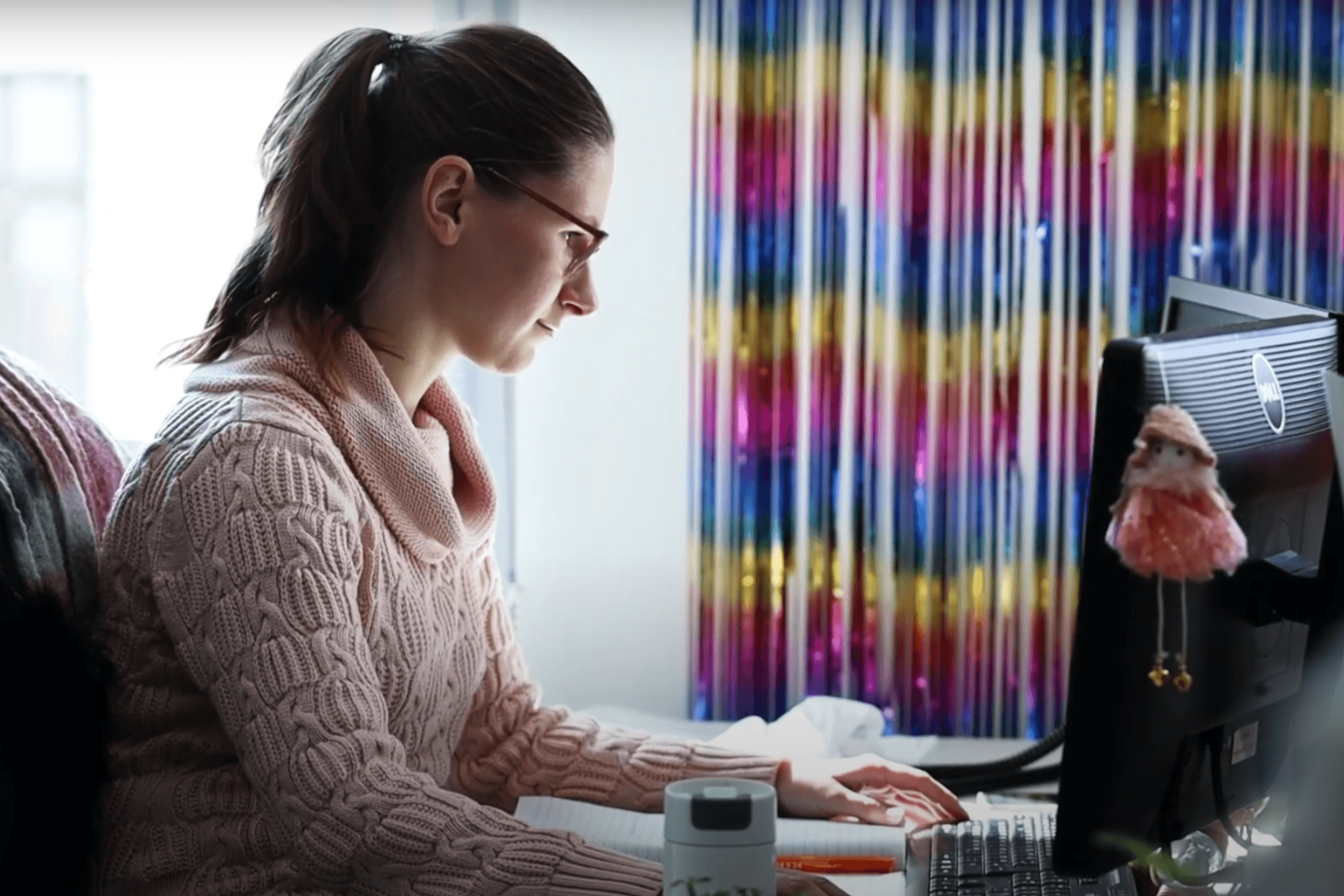 Gebietsleitung Eine Gebietsleiterin der Volkshilfe Wien sitzt konzentriert vor einem Computer und arbeitet. Sie trägt einen pinken Pullover und eine Brille. Der Schreibtisch ist stark dekoriert.